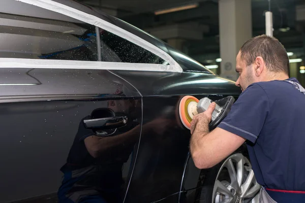 Un hombre pule un coche negro — Foto de Stock