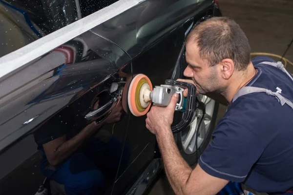 Un hombre pule un coche negro — Foto de Stock