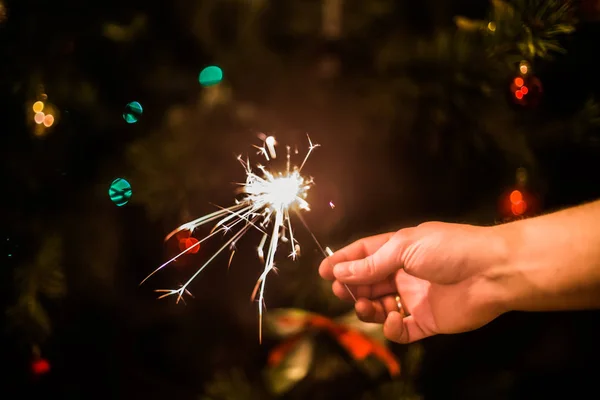 Xmas ağacı arka planında yanan maytaplı el