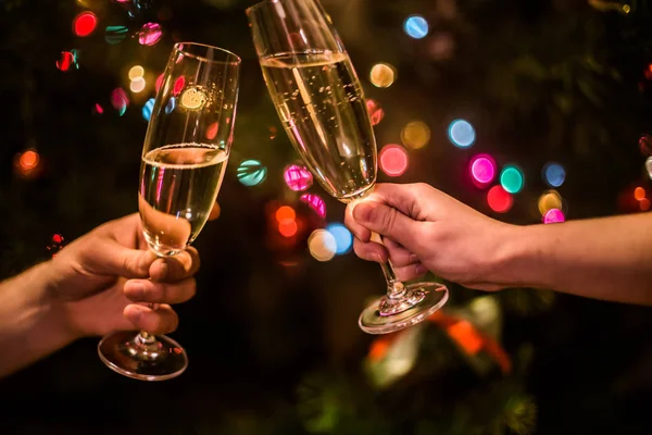 Elinde şampanya olan bir bardak Noel ağacı arka planında