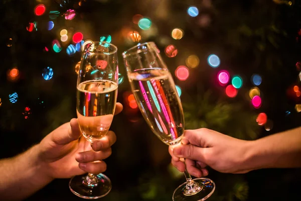 Elinde şampanya olan bir bardak Noel ağacı arka planında