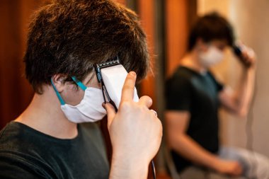  Evde saç kesimi, tıbbi maske takan bir kırpıcı.