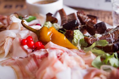 Soğuk aperatif: jambon, göğüs eti tuzlu, samanla tütsülenmiş göğüs eti, pastırma. Hardal sosu ve fırında soğanla servis edilir. Kahverengi arkaplan.