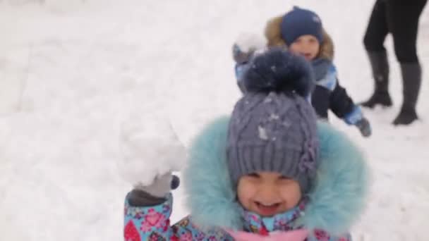 Děti tří až čtyř let hraje na sněhu s rodiči.