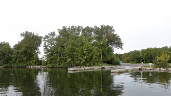 Bomen, rotsen en een boot starten aan de oever van een baai — Stockfoto
