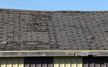 Old roof in disrepair with aged shingles on a small building clipart