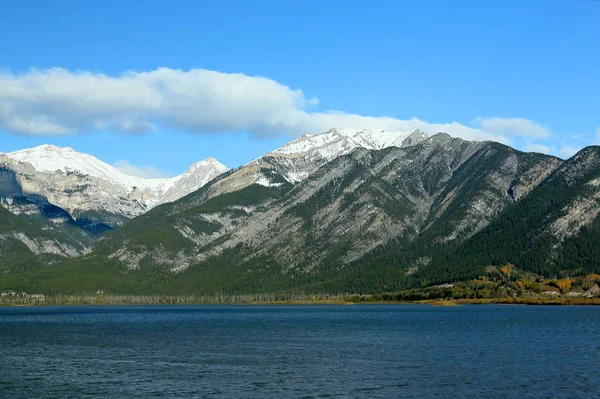 Céu azul com nuvens e lago azul com montanhas no fundo — Fotografia de Stock