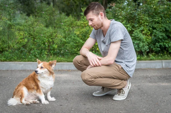 The young man walks with the dog on the street — Stock Photo, Image