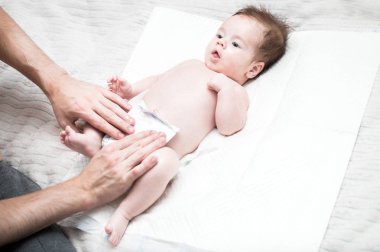 Genç baba bebeği için altını değiştiriyor. Beyaz arka plan. Yakın plan. Yeni doğan bakım konsepti.