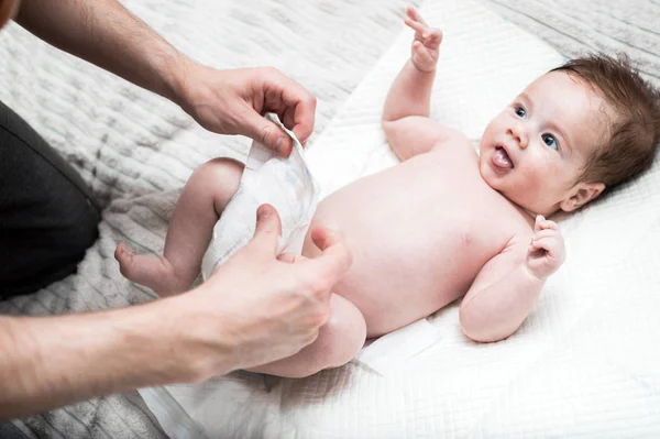 Young dad changes the diaper for his baby. White background. Close-up. Newborn care concept. — Stock Photo, Image