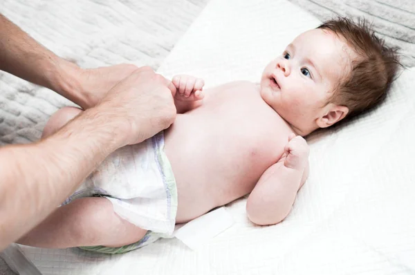 Young dad puts a fresh diaper on his baby. Close-up. Newborn care concept. Dad does hygiene to his baby — Stock Photo, Image