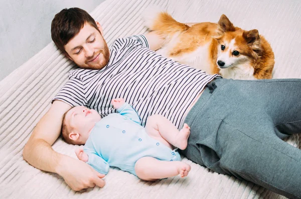 Joven se acuesta en una cama con un niño y su perro. Sonrisa, felicidad, risa, descanso. Concepto de niños y mascotas — Foto de Stock