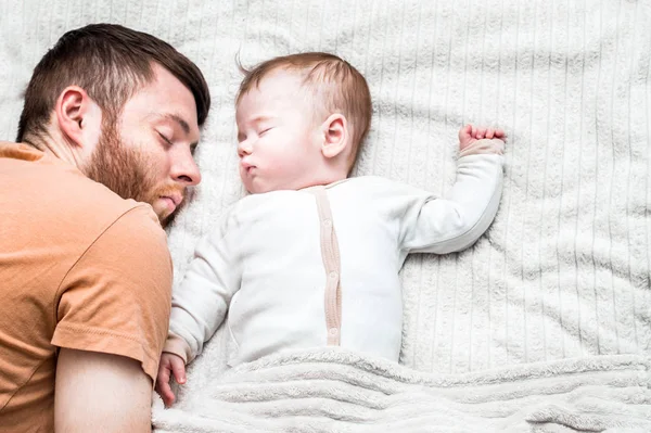 Close-up portrait of infant sleeping in bed in an embrace with his young father — Stock Photo, Image