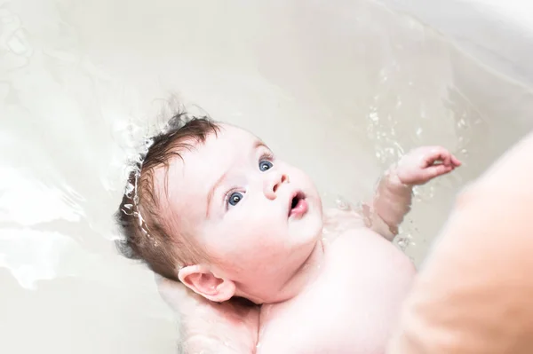 Baby bathes in the bath. Dad holds the baby in the water. Close up portrait — Stock Photo, Image