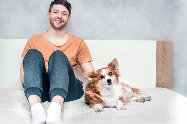 Jovem Está Sentado Cama Com Seu Cão Gengibre Retrato Close — Fotografia de Stock