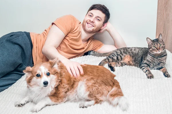 Sahibi köpeği ve kedisiyle birlikte yatakta sarılıyor. Evcil hayvanlar