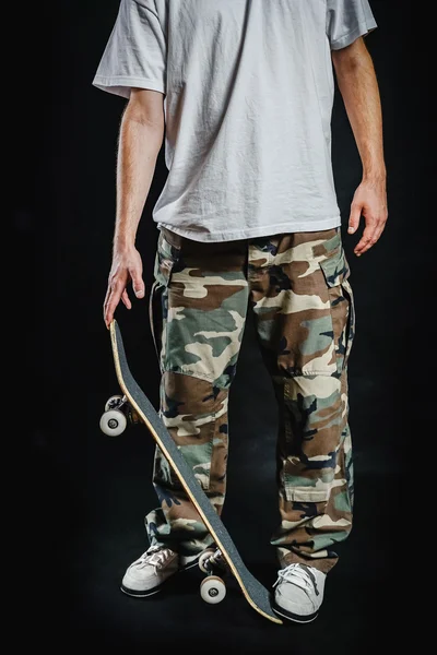 Uomo con skateboard su sfondo nero — Foto Stock