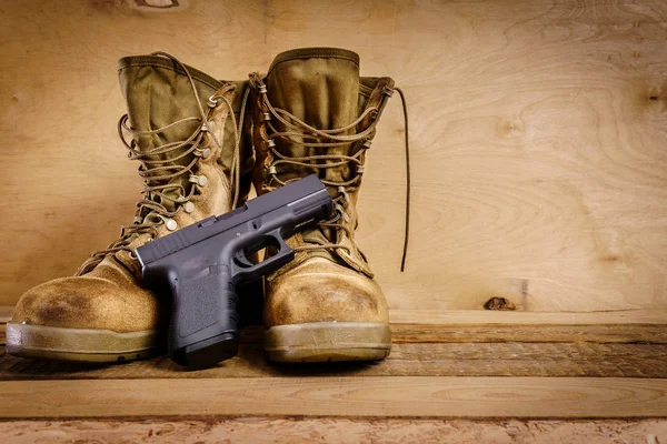 Военные сапоги и пистолет на столе — стоковое фото