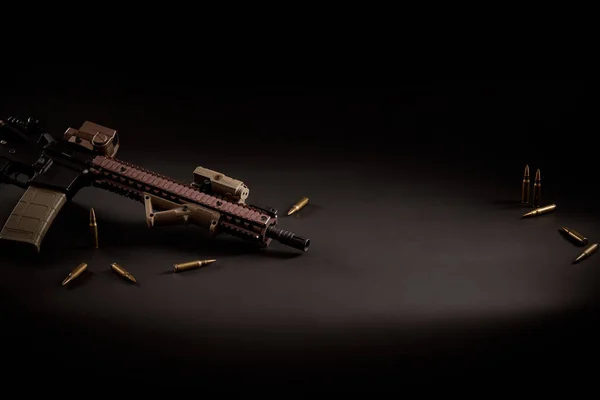 Rifle de assalto e balas douradas em um fundo preto — Fotografia de Stock