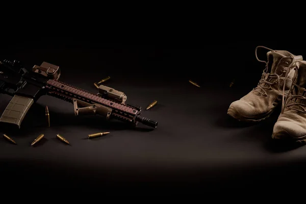 Rifle de assalto e botas militares em um fundo preto — Fotografia de Stock