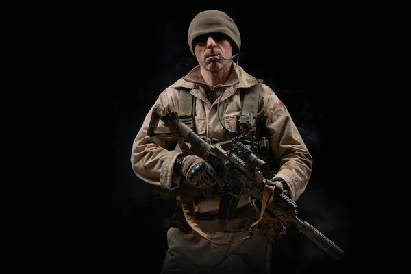 Forze speciali soldato posa con un fucile su uno sfondo nero — Foto Stock