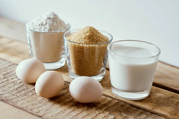 Latte, farina, zucchero e uova di pasta su un tavolo di legno — Foto Stock