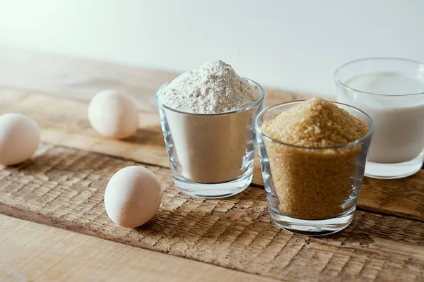 Süt, un, şeker ve hamur yumurta üzerinde ahşap bir masa — Stok fotoğraf