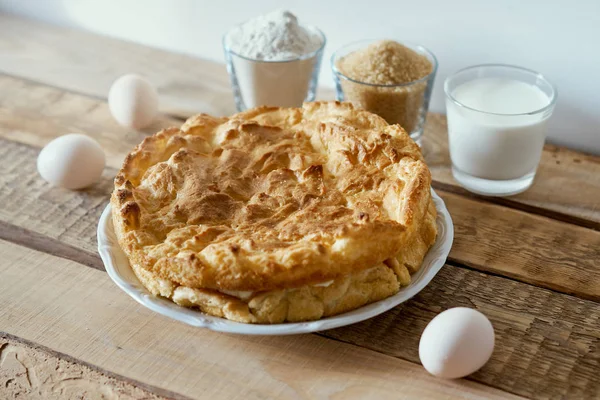 delicious cake, eggs, flour, milk and sugar on a wooden table