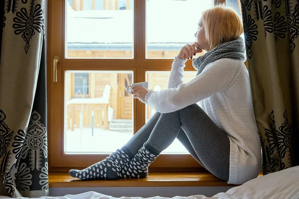 Woman sitting with a mug of tea in a winter window — Stock Photo, Image