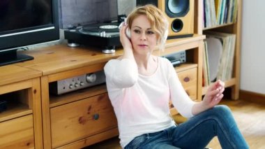 onun baş ve müzik dinler kulaklık ile bir pikap yanında oturan güzel kadın