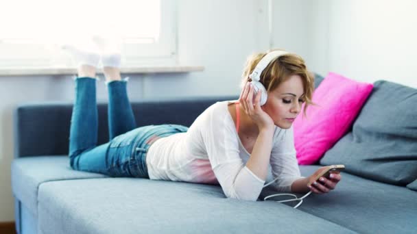 Beautiful Woman Lies Gray Sofa Headphones Her Head Listens Music — Stock Video