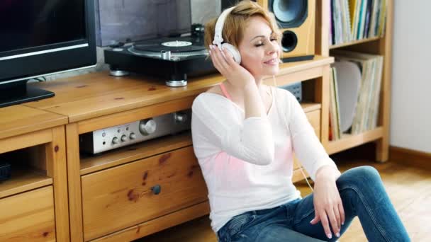 Красива Жінка Сидить Поруч Поворотним Столом Навушниками Голові Слухає Музику — стокове відео
