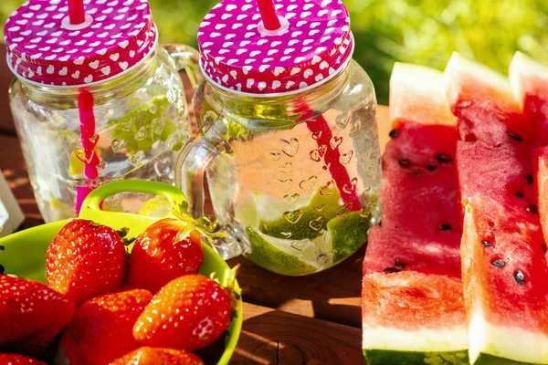 Twee glazen limonade en fruit op een picknicktafel — Stockfoto