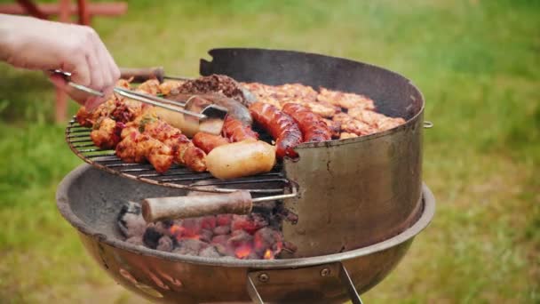 Zblízka Žena Ruky Držící Kleště Otáčení Grilovací Klobásky Grilu — Stock video