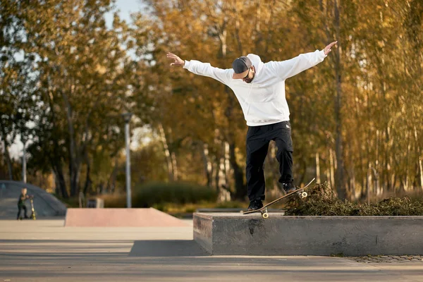 Uomo in skatepark cavalca skateboard nella calda giornata autunnale — Foto Stock