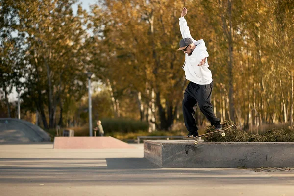 Uomo in skatepark cavalca skateboard nella calda giornata autunnale — Foto Stock