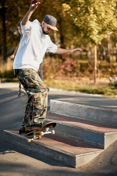Uomo in skatepark cavalca skateboard nella calda giornata autunnale — Foto Stock