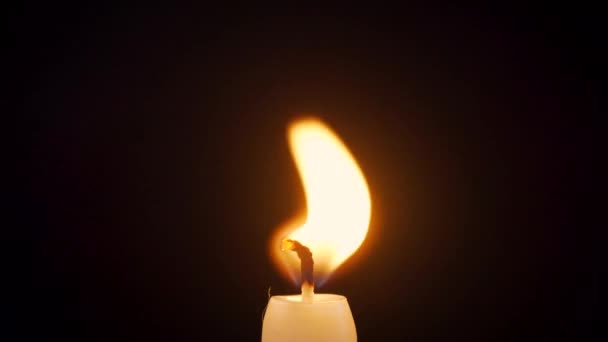 Primer plano de una vela encendida aislada sobre un fondo negro — Vídeo de stock