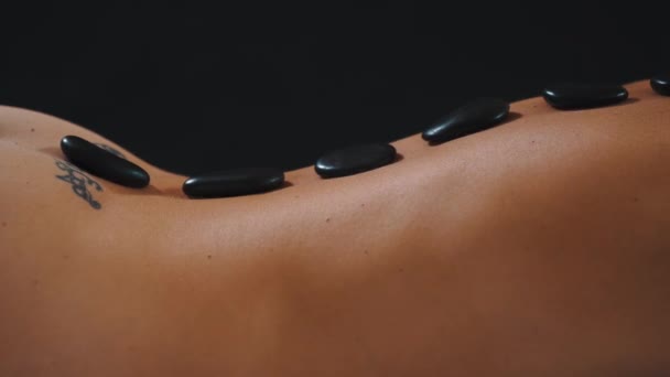 Massage aux pierres chaudes sur le dos d'une femme nue — Video