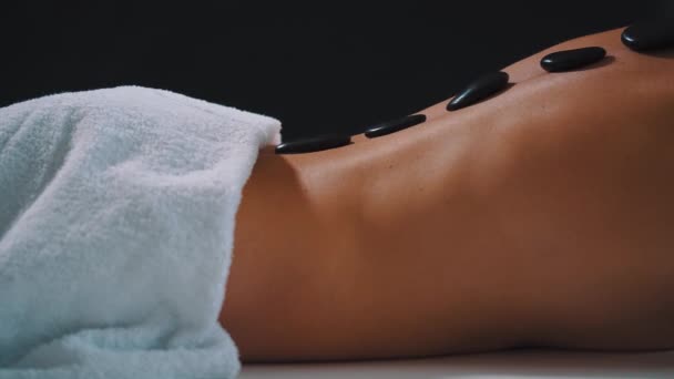 Massage aux pierres chaudes sur le dos d'une belle femme — Video