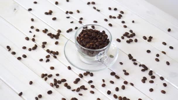 Copa de vidrio con granos de café en la mesa blanca — Vídeos de Stock