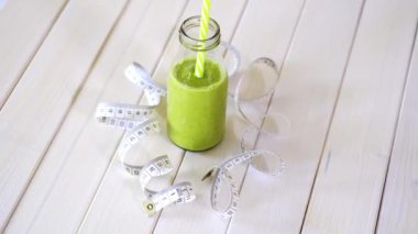 beyaz ahşap masa üzerinde santimetre bant ile sağlıklı yeşil ve vegan kokteyl