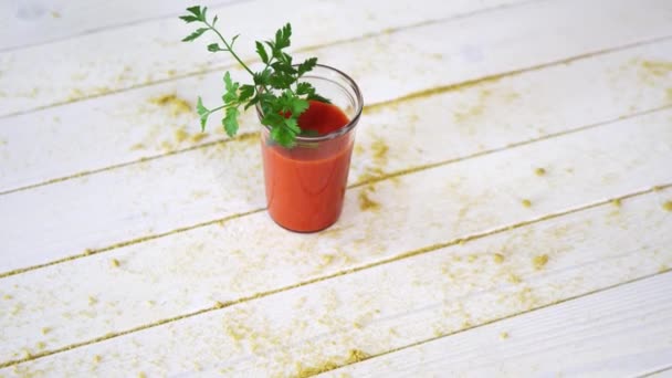 Gesunde Tomate und veganer Cocktail mit Petersilienzweig auf weißem Holztisch mit Sand — Stockvideo