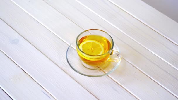 Geleneksel çin çayı ve beyaz masada limon dilimi ile Cam fincan. — Stok video