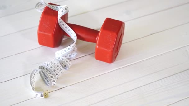 Mancuerna de fitness roja y cinta de centímetro en mesa de madera blanca — Vídeos de Stock
