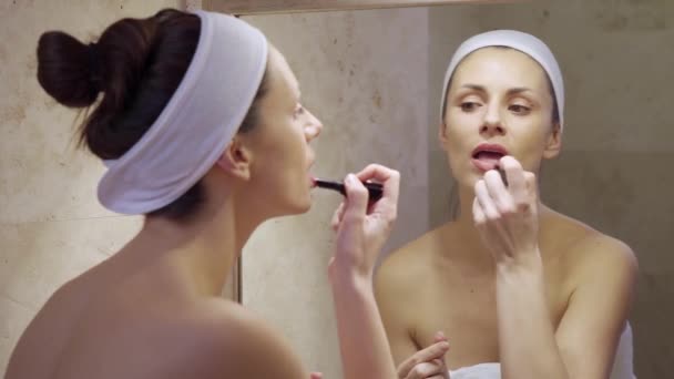 Mooie jonge vrouw zetten rode lippenstift en kijken in spiegel. — Stockvideo