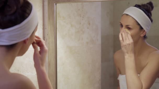 Krásná mladá žena aplikuje tekutiny při pohledu do zrcadla — Stock video