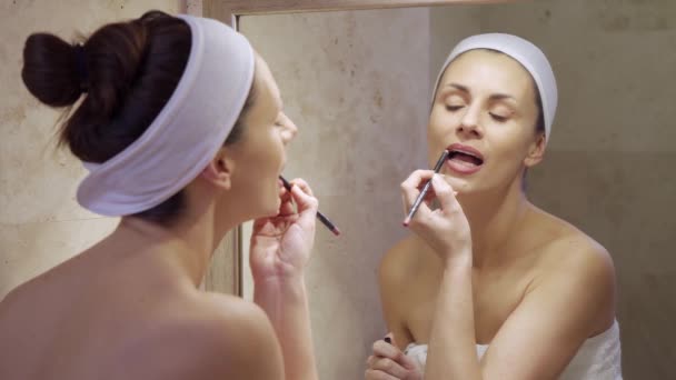 Hermosa mujer joven poniendo lápiz labial rojo y mirando en el espejo . — Vídeos de Stock