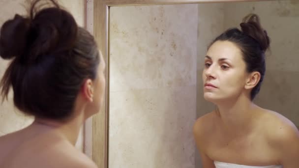 Mooie jonge vrouw doen make-up verwijderen in de spiegel — Stockvideo