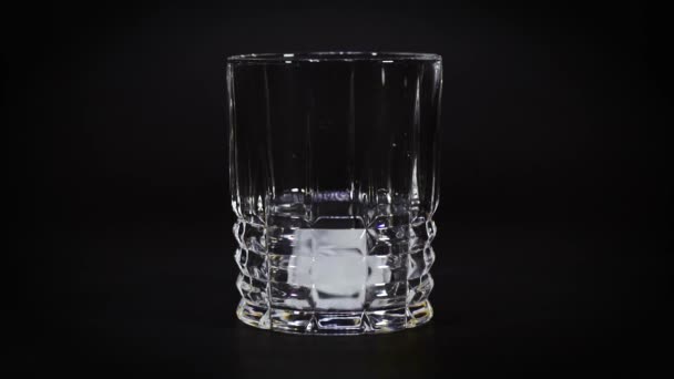 zwei Eiswürfel fallen in ein leeres Glas